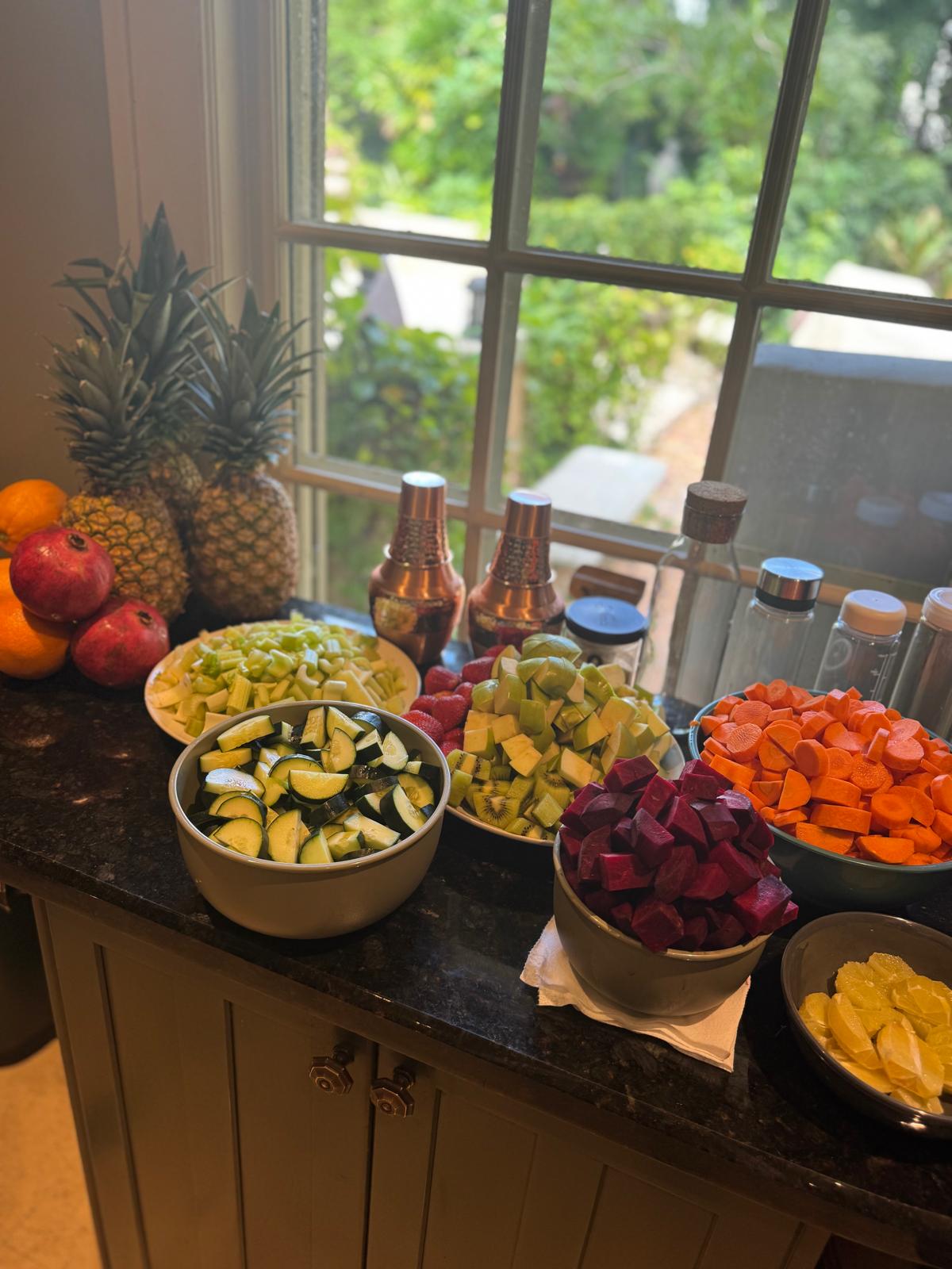 Prepped bowls of vegetables and fruit on a counter.